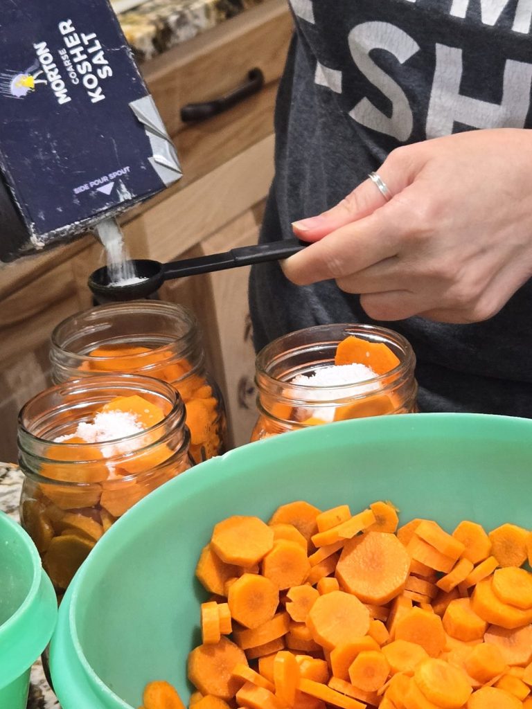 Adding salt to jars of carrots and peas