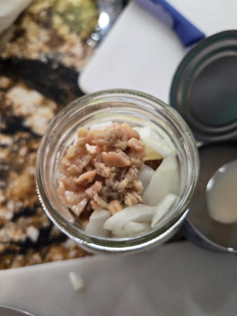 Minced clams added on top of potatoes and onions in a pint jar