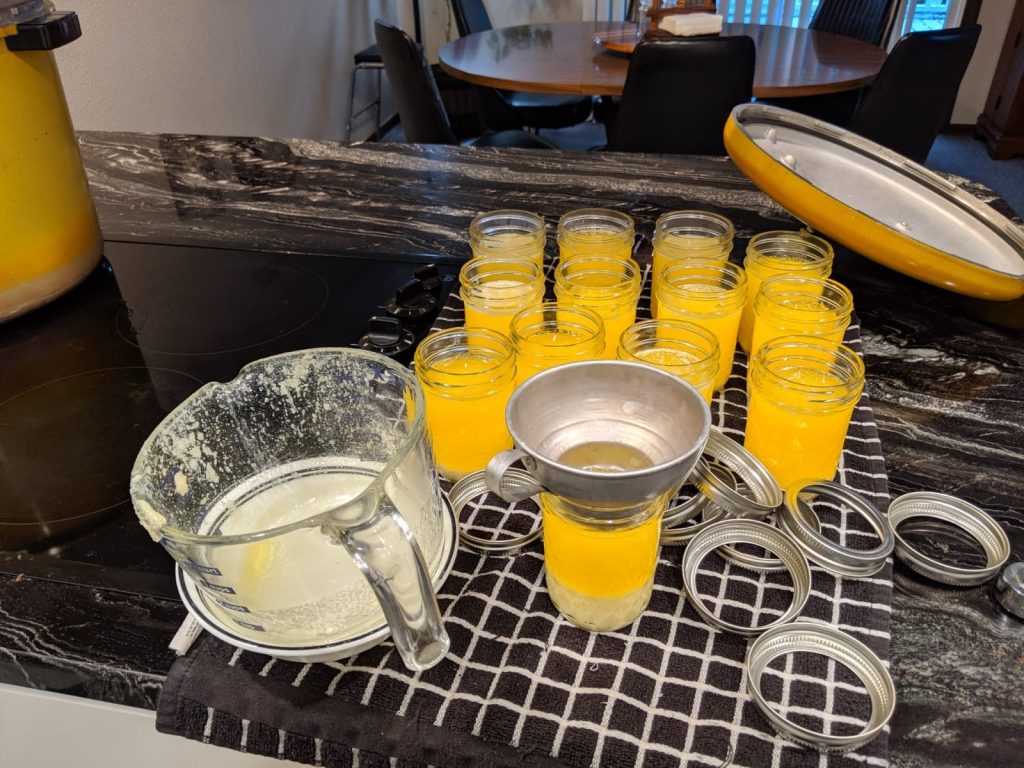 Funneling melted golden butter into small jars