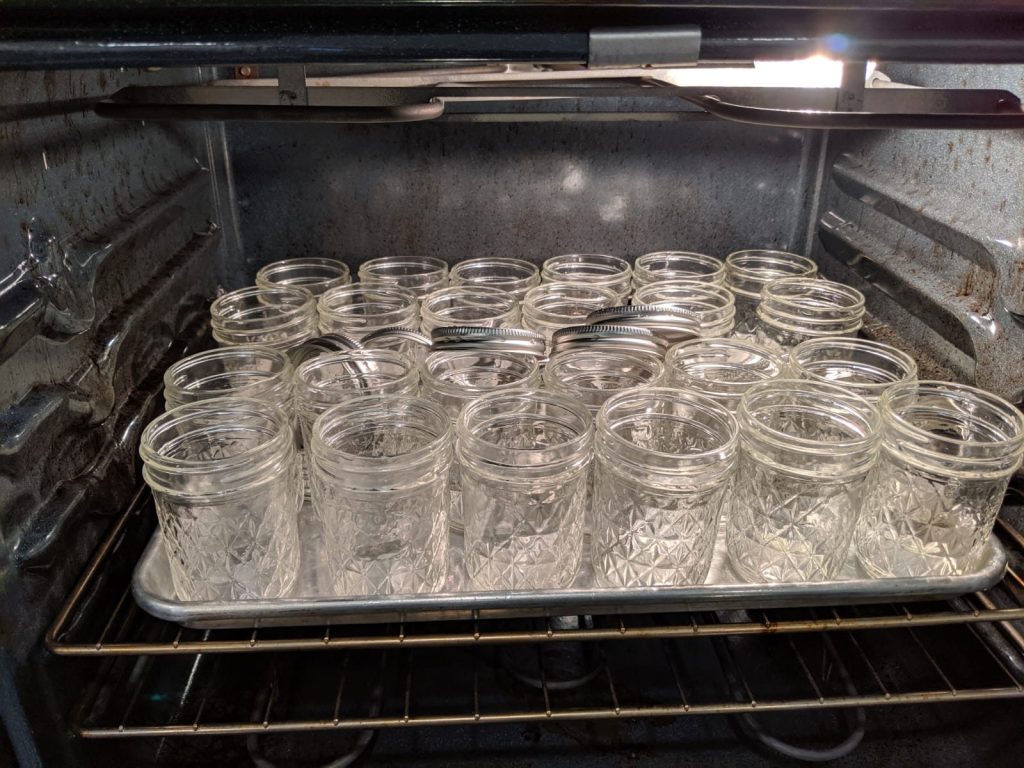 Clean empty jars warming on a tray in the oven